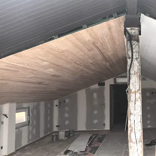 Ático de una vivienda en reformas con las paredes, techos y suelos sin pintar.