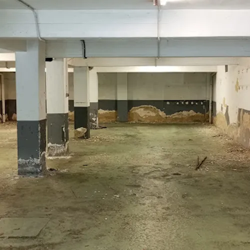 Garaje de almacenamiento de coches con necesidad de reforma por sus agujeros de paredes y falta de pintura..