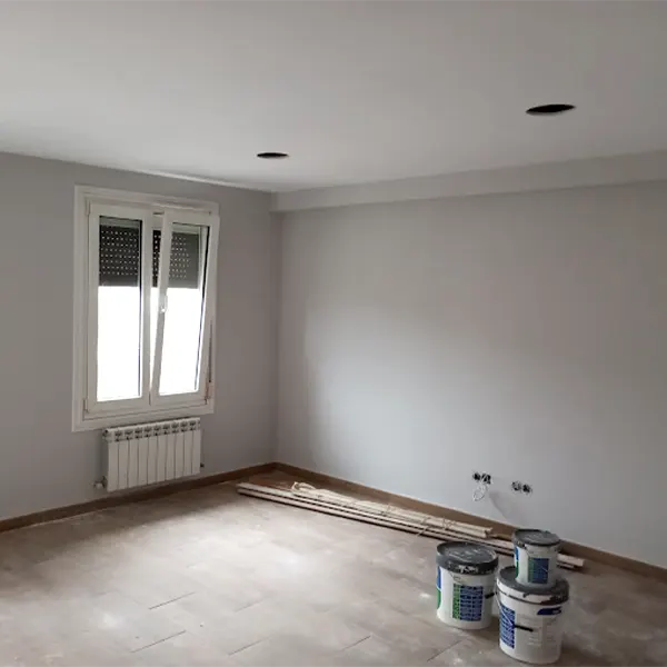 Habitación con paredes recién pintadas se blanco y con una ventada al exterior de la vivienda.