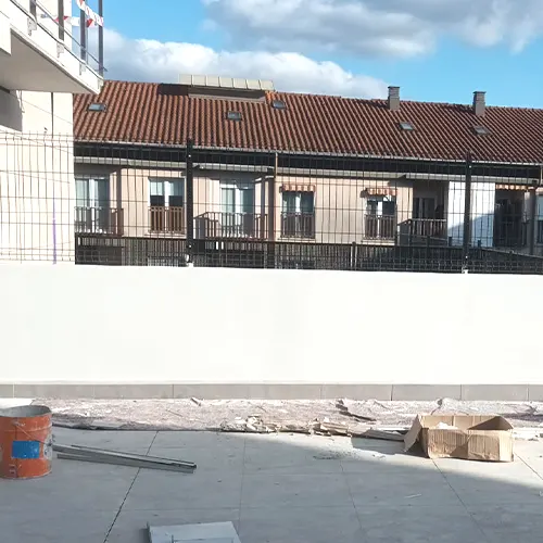 Amplia terraza exterior de vivieda con la pared recién pintada de blanco.