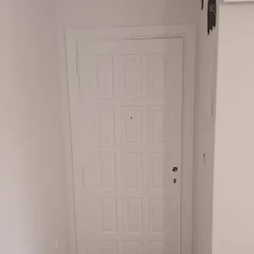 Puerta principal de vivienda de madera pintada de blanco.